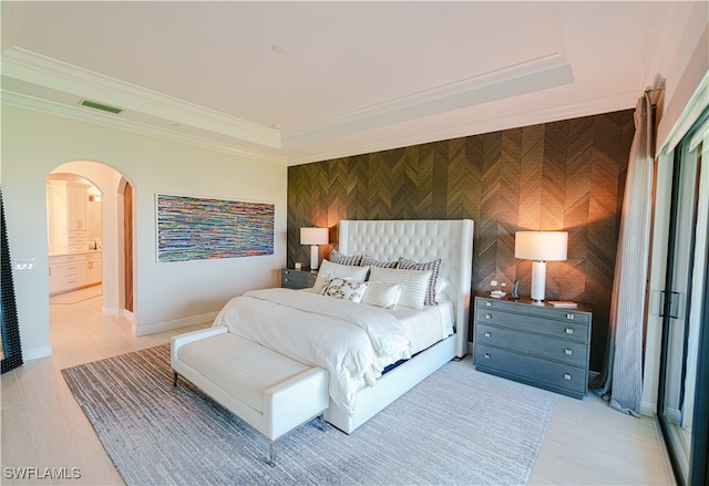 bedroom with ensuite bathroom, light hardwood / wood-style floors, and crown molding