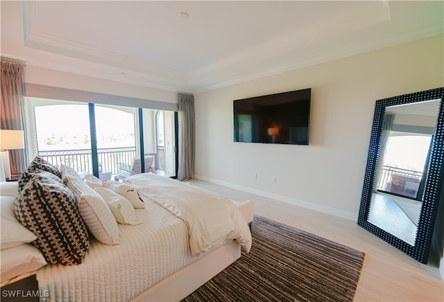 bedroom featuring access to outside, a raised ceiling, crown molding, and light hardwood / wood-style floors