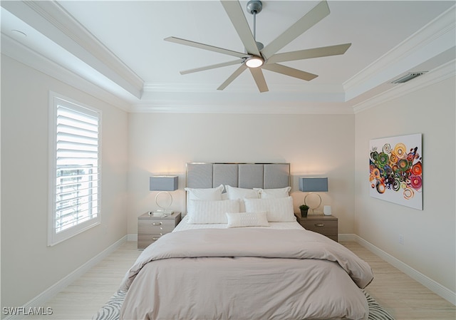 bedroom with light wood-type flooring, a tray ceiling, ceiling fan, and ornamental molding