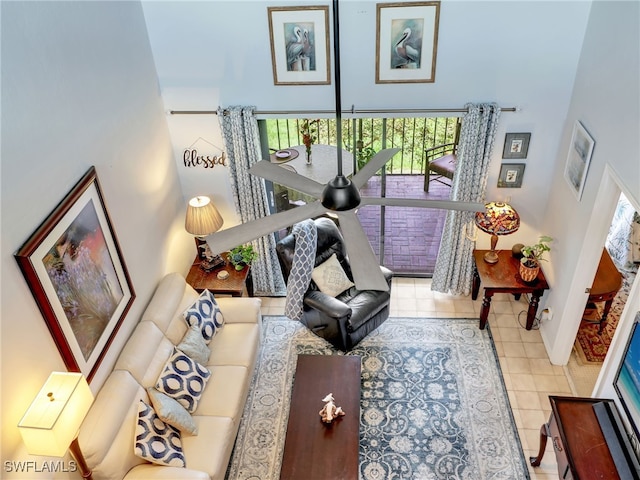 living room featuring ceiling fan, light tile patterned flooring, and a towering ceiling