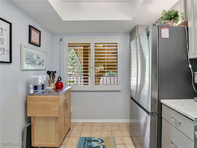 kitchen with light brown cabinetry, light tile patterned floors, and stainless steel fridge