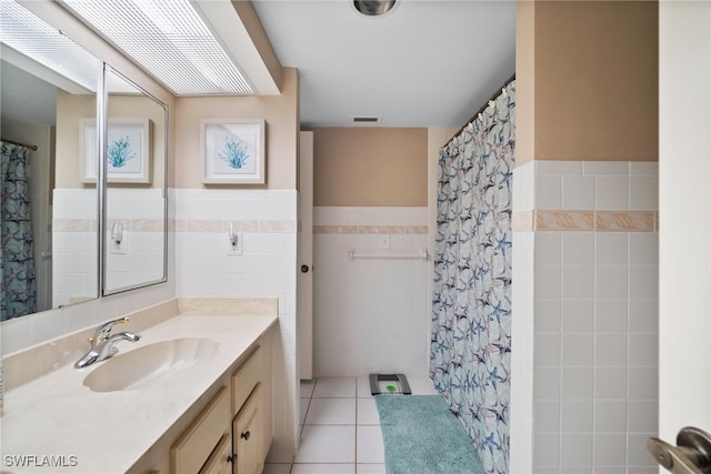 bathroom featuring vanity, tile patterned flooring, tile walls, and walk in shower