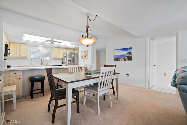 dining area with light colored carpet, sink, and ceiling fan