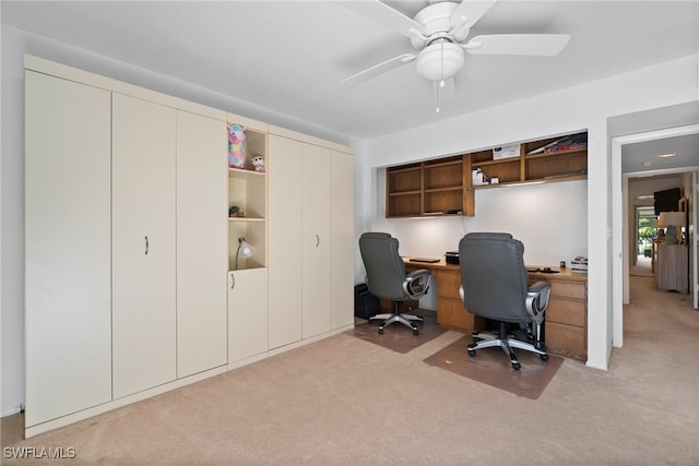 carpeted office featuring ceiling fan and built in desk