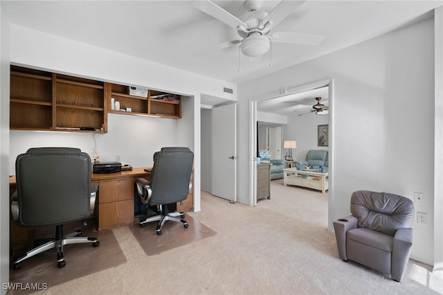 office space with built in desk, light colored carpet, and ceiling fan