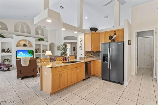 kitchen featuring light stone counters, kitchen peninsula, stainless steel appliances, ceiling fan, and sink