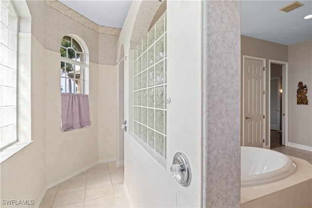 bathroom with tiled tub and tile patterned floors