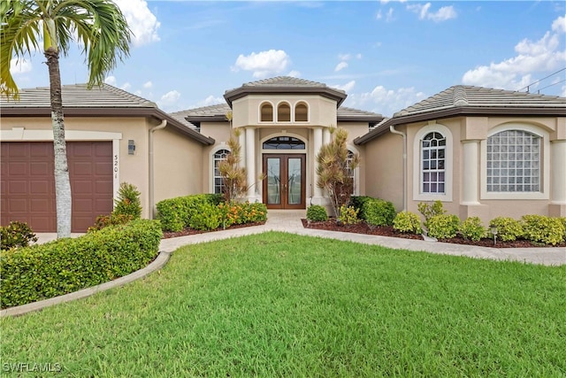 doorway to property featuring french doors, a garage, and a lawn