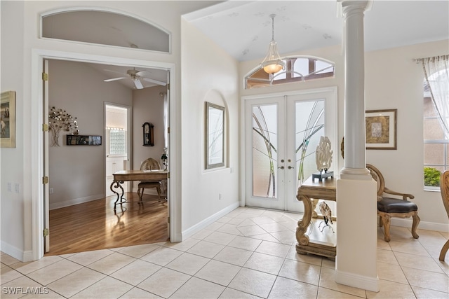 foyer entrance featuring light wood-type flooring, ceiling fan with notable chandelier, decorative columns, and french doors