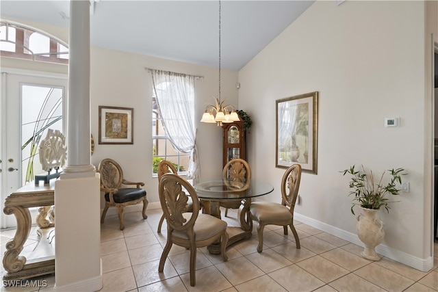 dining area featuring light tile patterned floors, a notable chandelier, decorative columns, and high vaulted ceiling