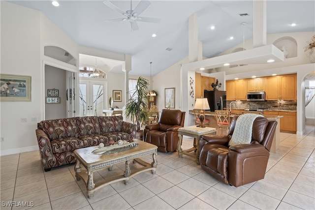 living room featuring ceiling fan with notable chandelier, sink, light tile patterned floors, and high vaulted ceiling