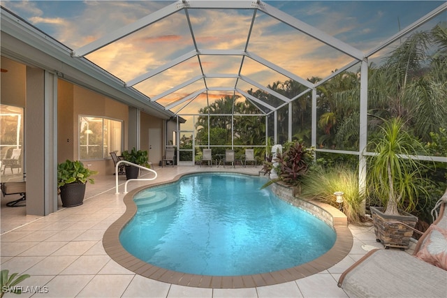 pool at dusk featuring a lanai, pool water feature, and a patio area