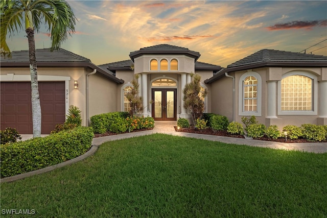 view of front of home featuring french doors, a garage, and a yard