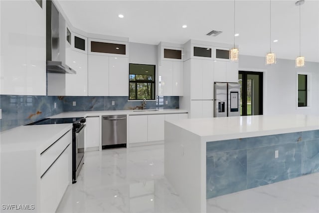 kitchen featuring white cabinets, hanging light fixtures, a kitchen island, wall chimney range hood, and stainless steel appliances