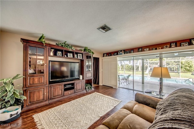 living room with a textured ceiling and dark hardwood / wood-style floors