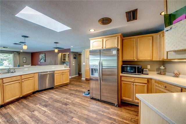 kitchen with a skylight, light brown cabinets, sink, stainless steel appliances, and dark hardwood / wood-style floors