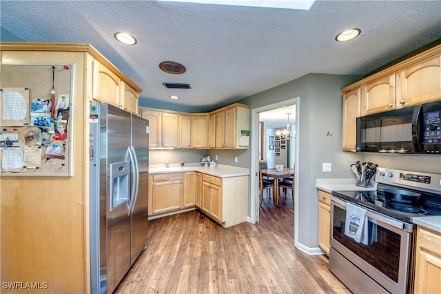 kitchen featuring an inviting chandelier, light wood-type flooring, a textured ceiling, light brown cabinetry, and appliances with stainless steel finishes