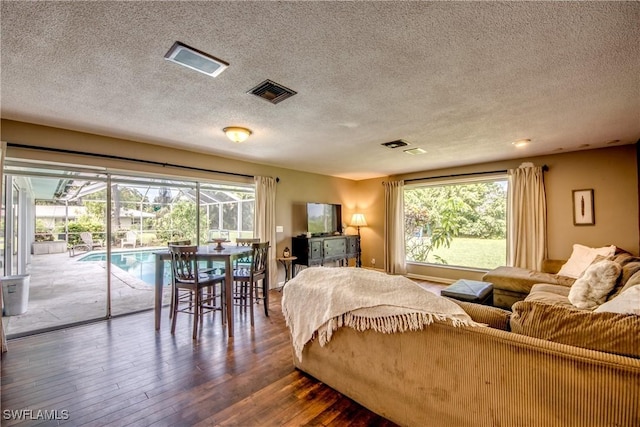 bedroom featuring hardwood / wood-style floors, a textured ceiling, access to outside, and multiple windows