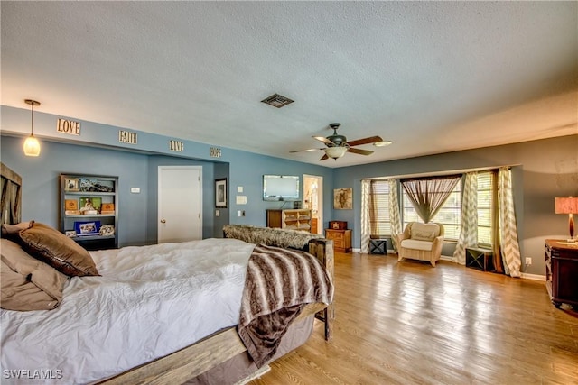 bedroom featuring ceiling fan, wood-type flooring, and a textured ceiling