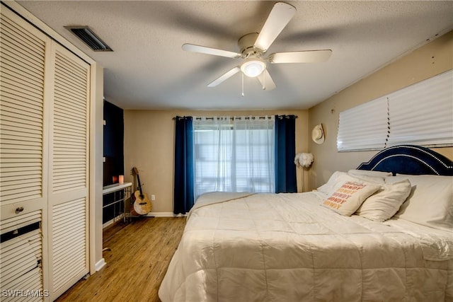 bedroom featuring ceiling fan, a closet, hardwood / wood-style floors, and a textured ceiling