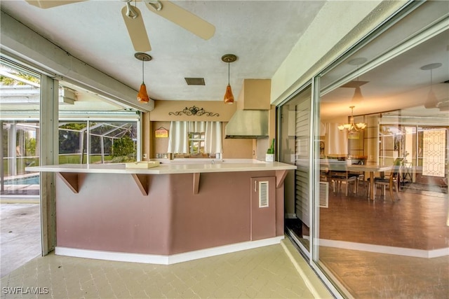 kitchen with a breakfast bar, kitchen peninsula, hanging light fixtures, and ceiling fan with notable chandelier