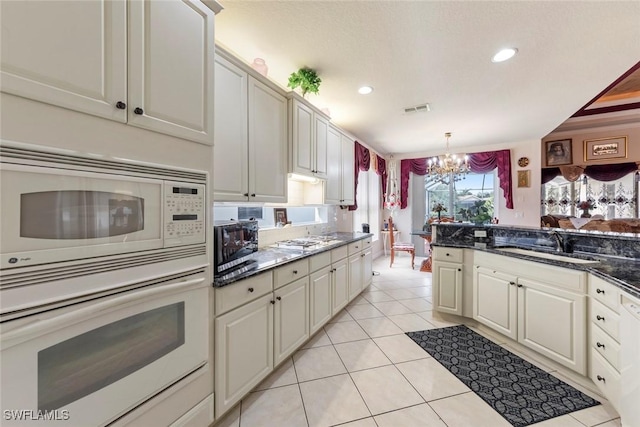 kitchen with visible vents, a sink, white appliances, a chandelier, and light tile patterned flooring
