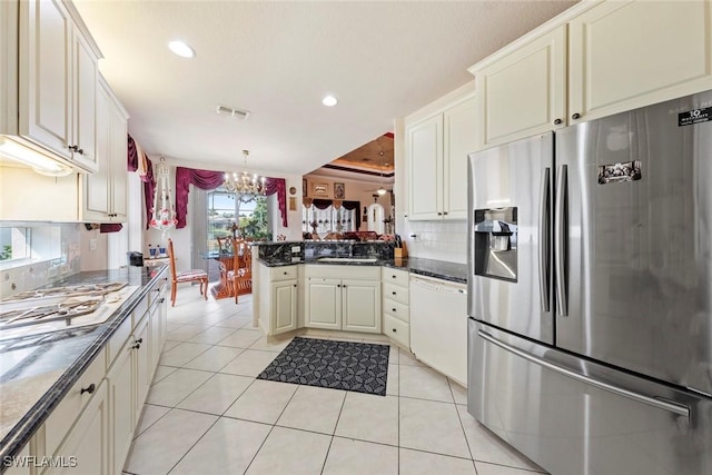 kitchen featuring a peninsula, tasteful backsplash, stainless steel refrigerator with ice dispenser, a chandelier, and dishwasher