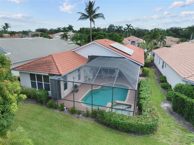 back of property with a tiled roof, a patio area, a lawn, glass enclosure, and stucco siding