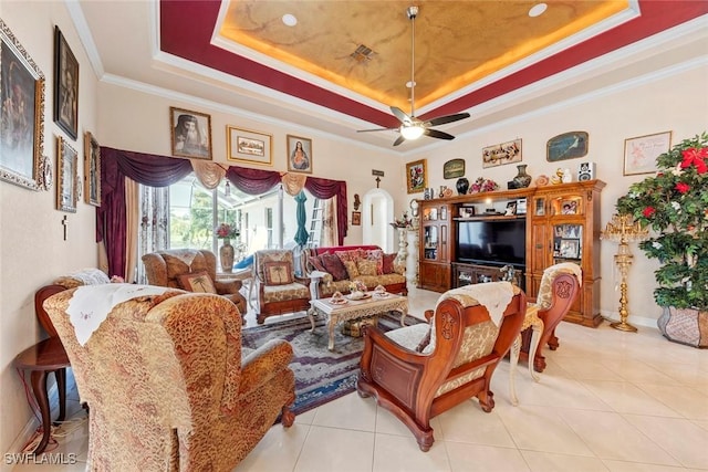 living area with light tile patterned floors, ornamental molding, a ceiling fan, and a raised ceiling