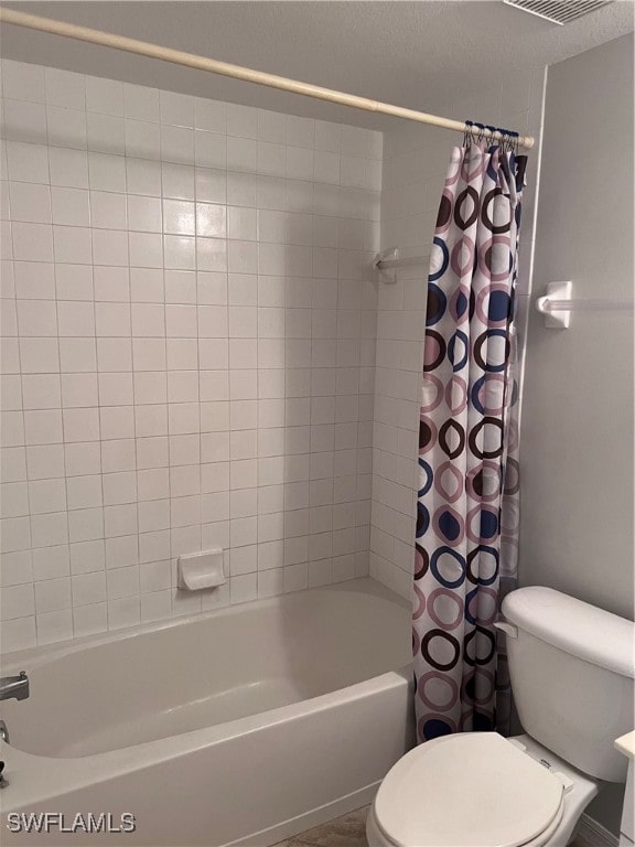 bathroom featuring shower / tub combo with curtain, a textured ceiling, and toilet