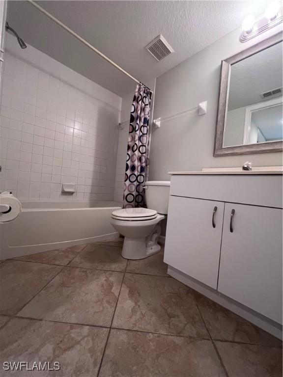 full bathroom featuring shower / bath combination with curtain, vanity, toilet, a textured ceiling, and tile patterned flooring