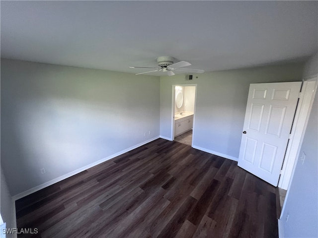 unfurnished bedroom with ceiling fan, ensuite bath, and dark wood-type flooring