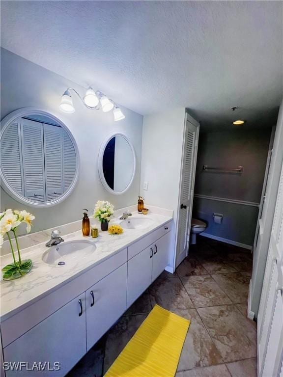 bathroom featuring toilet, vanity, and a textured ceiling