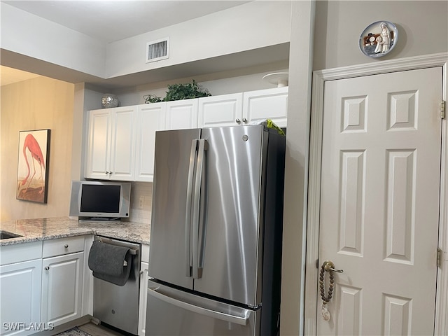 kitchen featuring light stone counters, stainless steel appliances, decorative backsplash, and white cabinets