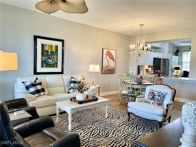 living room featuring wood-type flooring and ceiling fan with notable chandelier