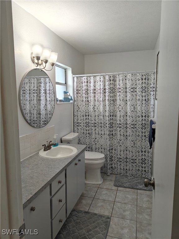 bathroom featuring vanity, toilet, tile patterned floors, and a shower with curtain