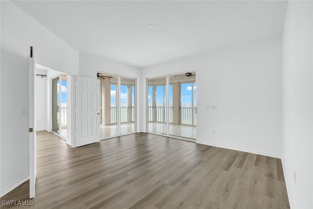 empty room featuring baseboards, wood finished floors, and a ceiling fan