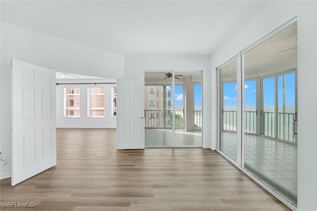 empty room featuring a healthy amount of sunlight, ceiling fan, and wood finished floors