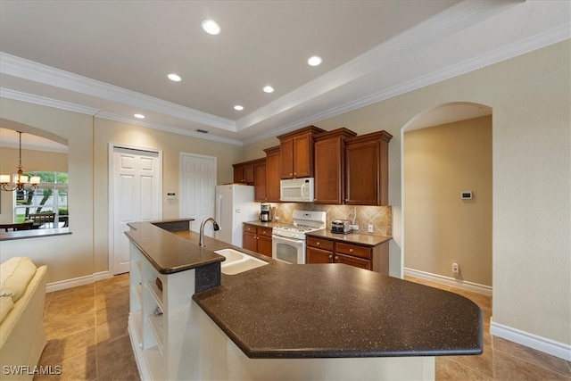 kitchen with tasteful backsplash, white appliances, crown molding, sink, and a center island with sink