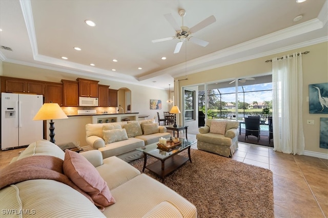 tiled living room with a tray ceiling, ceiling fan, and ornamental molding