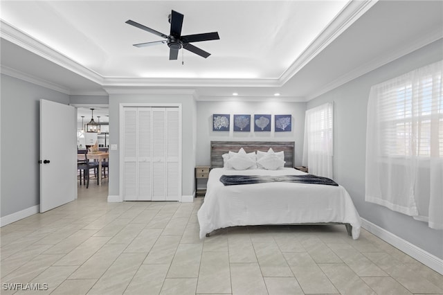 tiled bedroom with ceiling fan with notable chandelier, a tray ceiling, crown molding, and a closet