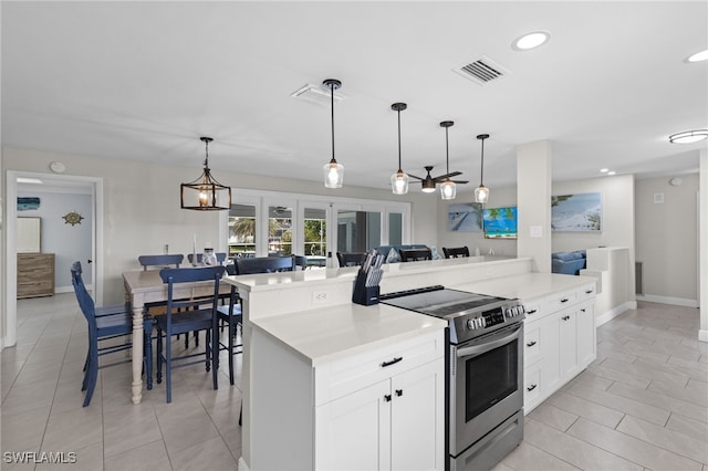 kitchen featuring a kitchen breakfast bar, electric stove, a center island, white cabinetry, and decorative light fixtures