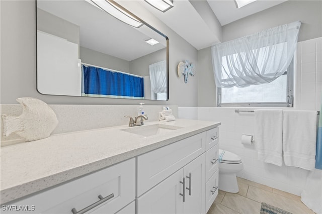 bathroom with tile walls, tile patterned flooring, toilet, and vanity