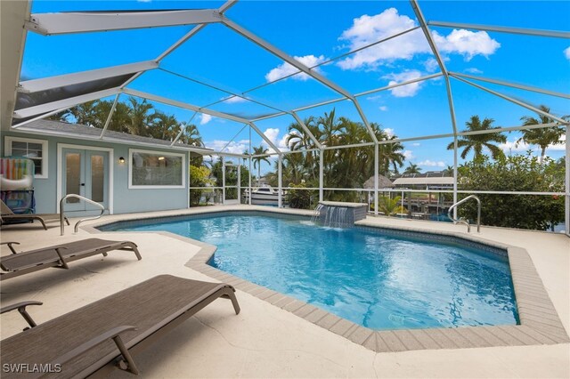 view of pool with pool water feature, a lanai, french doors, and a patio