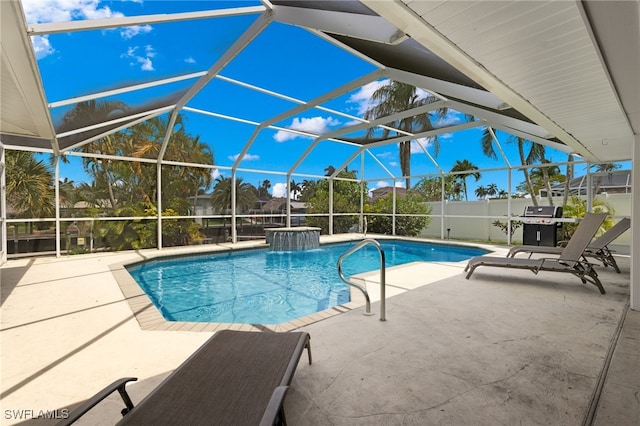 view of pool with a patio, glass enclosure, and pool water feature