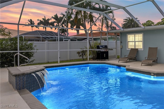 pool at dusk featuring pool water feature, a lanai, area for grilling, and a patio