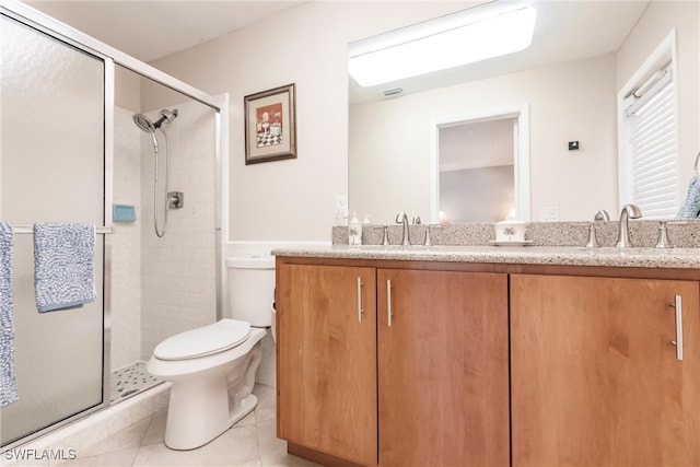 bathroom with tile patterned flooring, vanity, a shower with shower door, and toilet