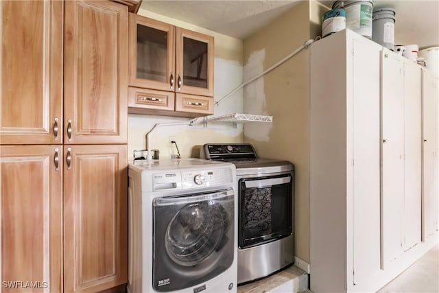 clothes washing area with cabinets and independent washer and dryer