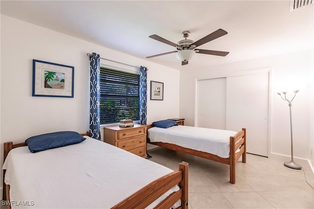 tiled bedroom featuring ceiling fan and a closet