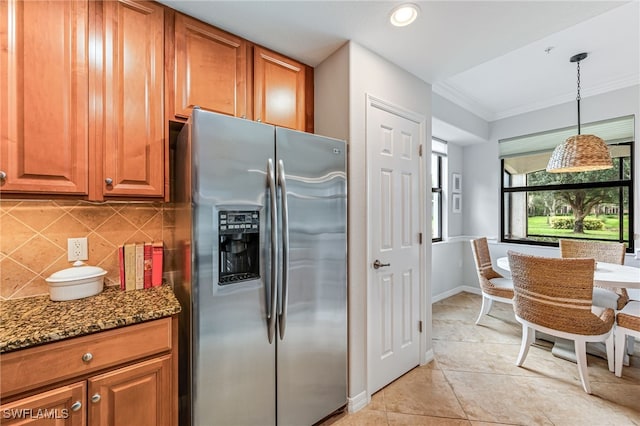 kitchen featuring pendant lighting, stainless steel fridge with ice dispenser, dark stone counters, crown molding, and decorative backsplash